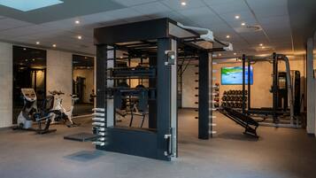 Un gimnasio con diversos equipos de ejercicio, como una estructura para sentadillas, cintas de correr y mancuernas.
