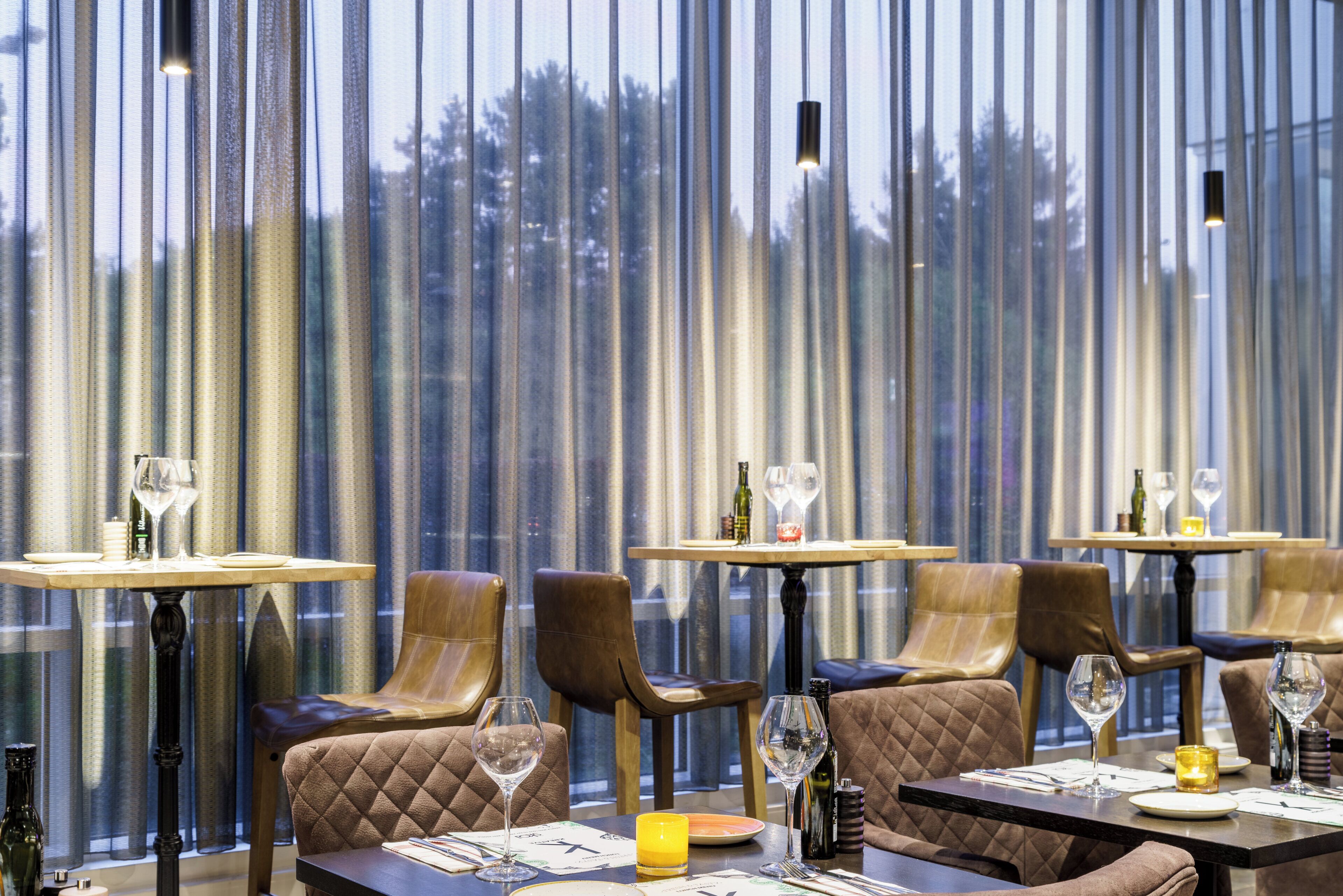 A restaurant interior with leather seating, tables, and wine glasses.