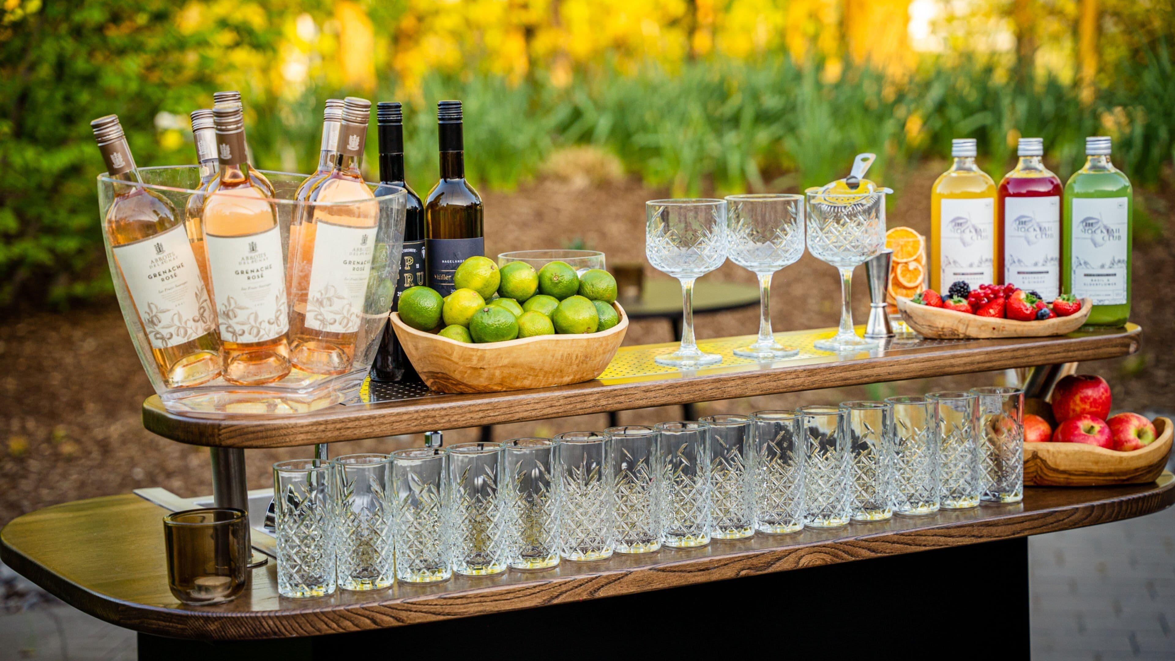 Disposición de bar con botellas, vasos y frutas.