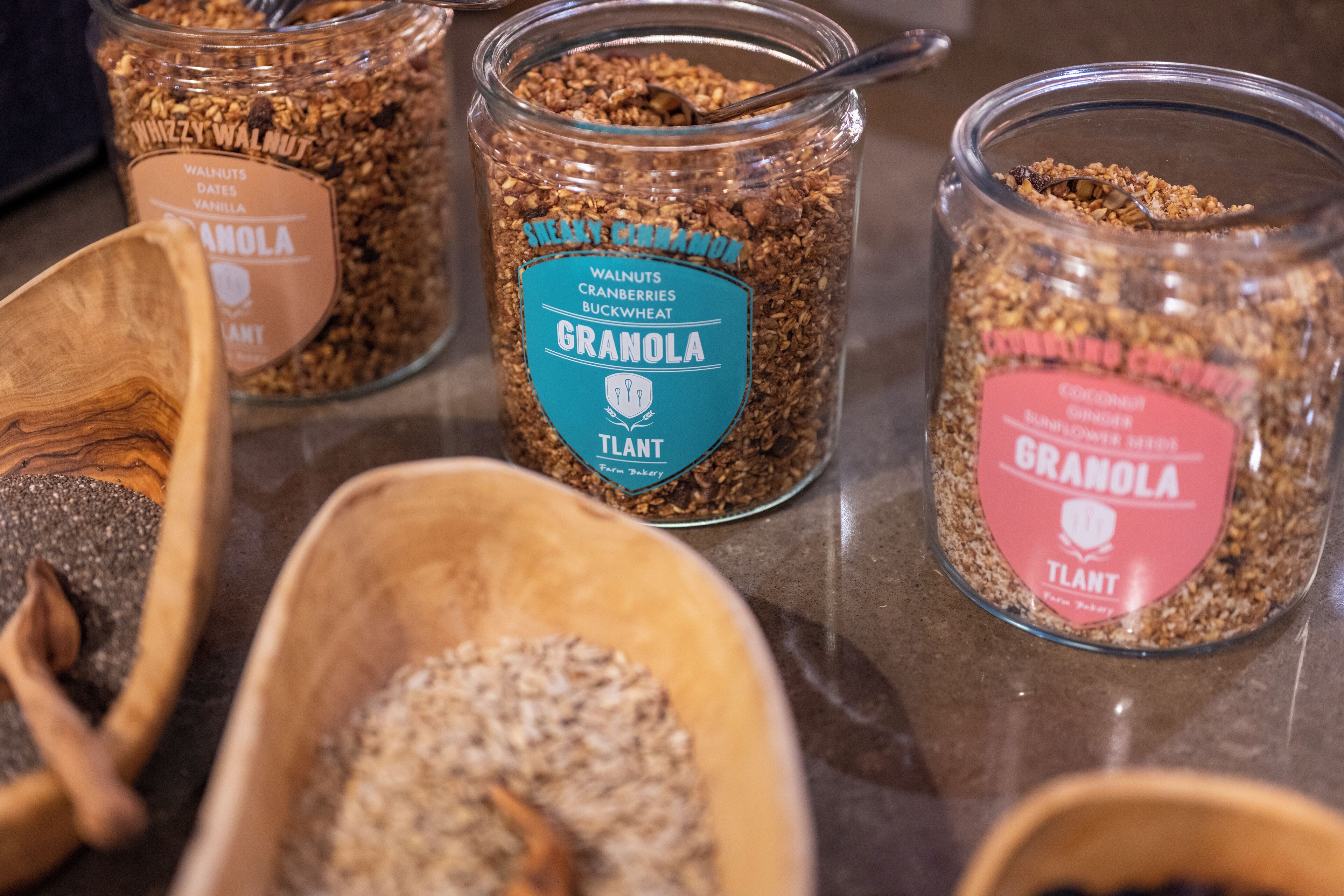 Three glass jars of granola with different flavors and ingredients, placed on a countertop.