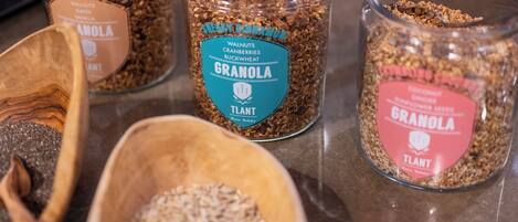 Three glass jars of granola with different flavors and ingredients, placed on a countertop.