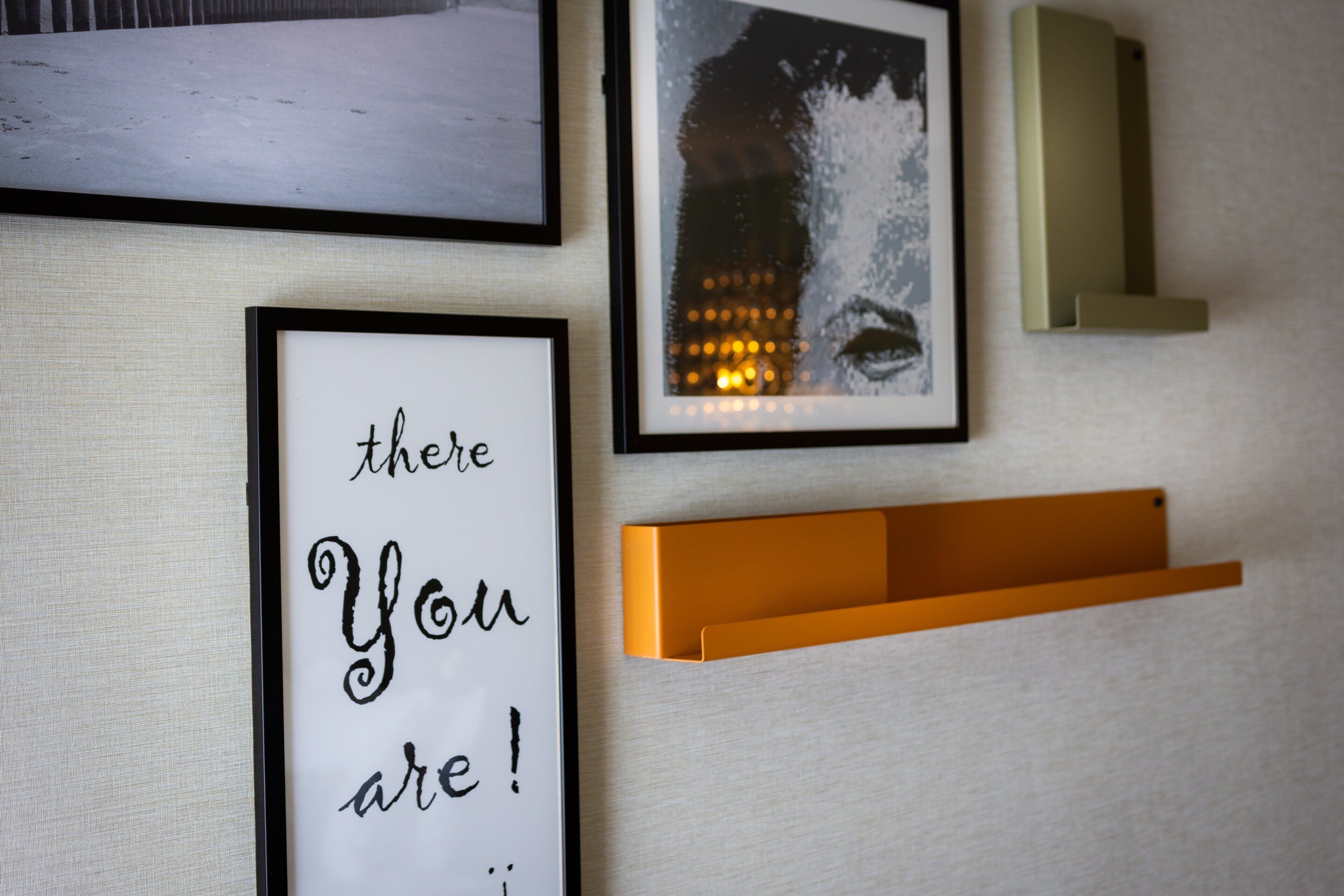 A wall with framed artwork, including a quote and a portrait.