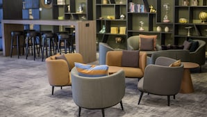 A modern lounge area with sofas, armchairs, and a bar area with stools.