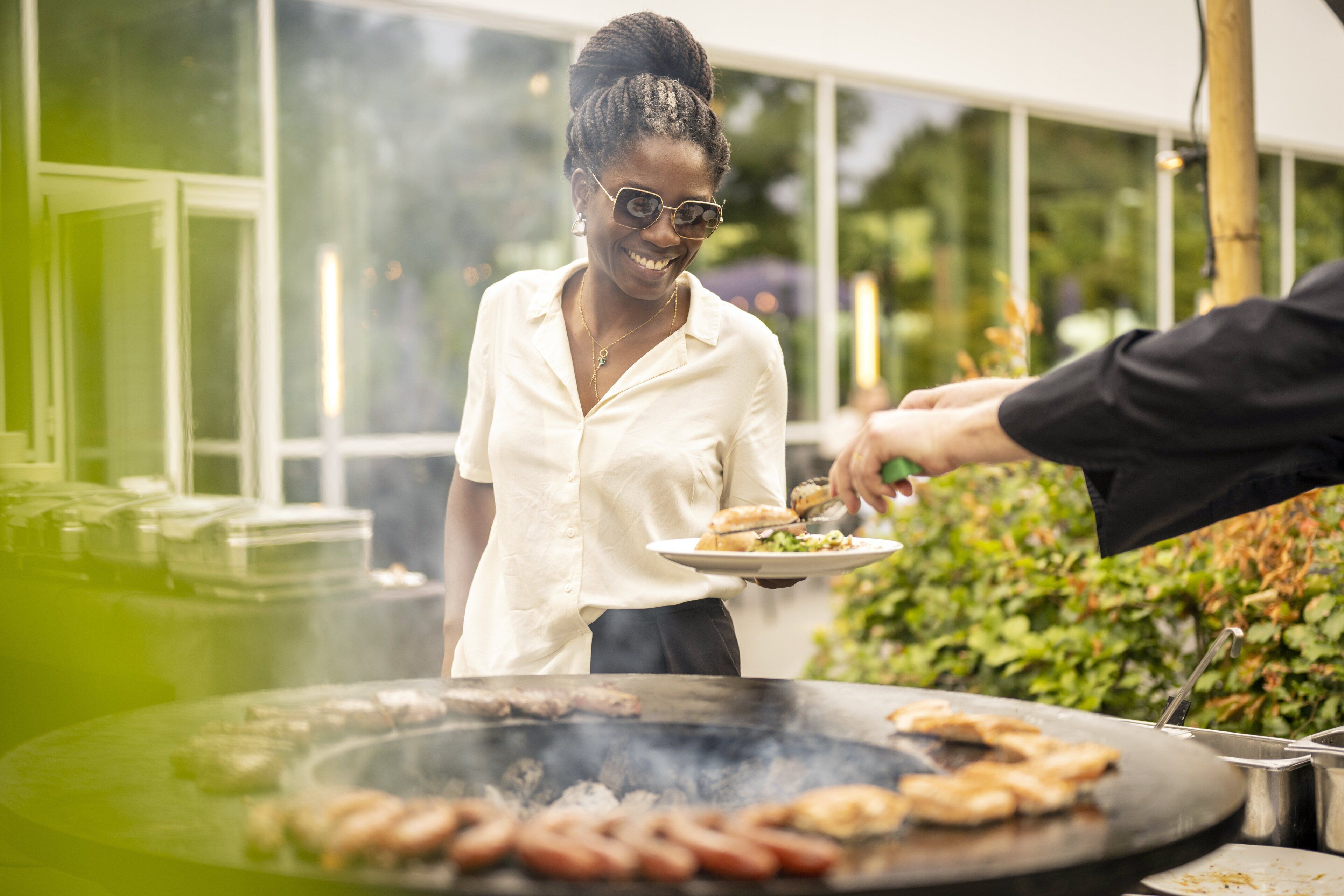 Una persona sirviendo comida de una parrilla al aire libre.