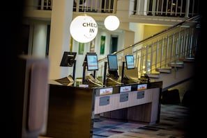 A reception desk with a 'Check In' sign, a staircase, and a view of the lobby area. - Holiday Inn Brussels Airport by IHG (Machelen)