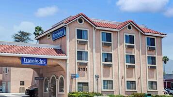 Classic hotel building with a red-tiled roof and beige facade, featuring a mix of single and double-hung windows.