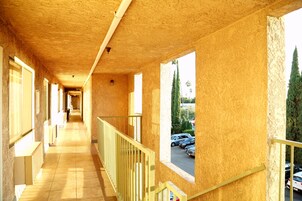 Un pasillo con techo de madera, ventanas amplias y vistas a coches aparcados afuera.