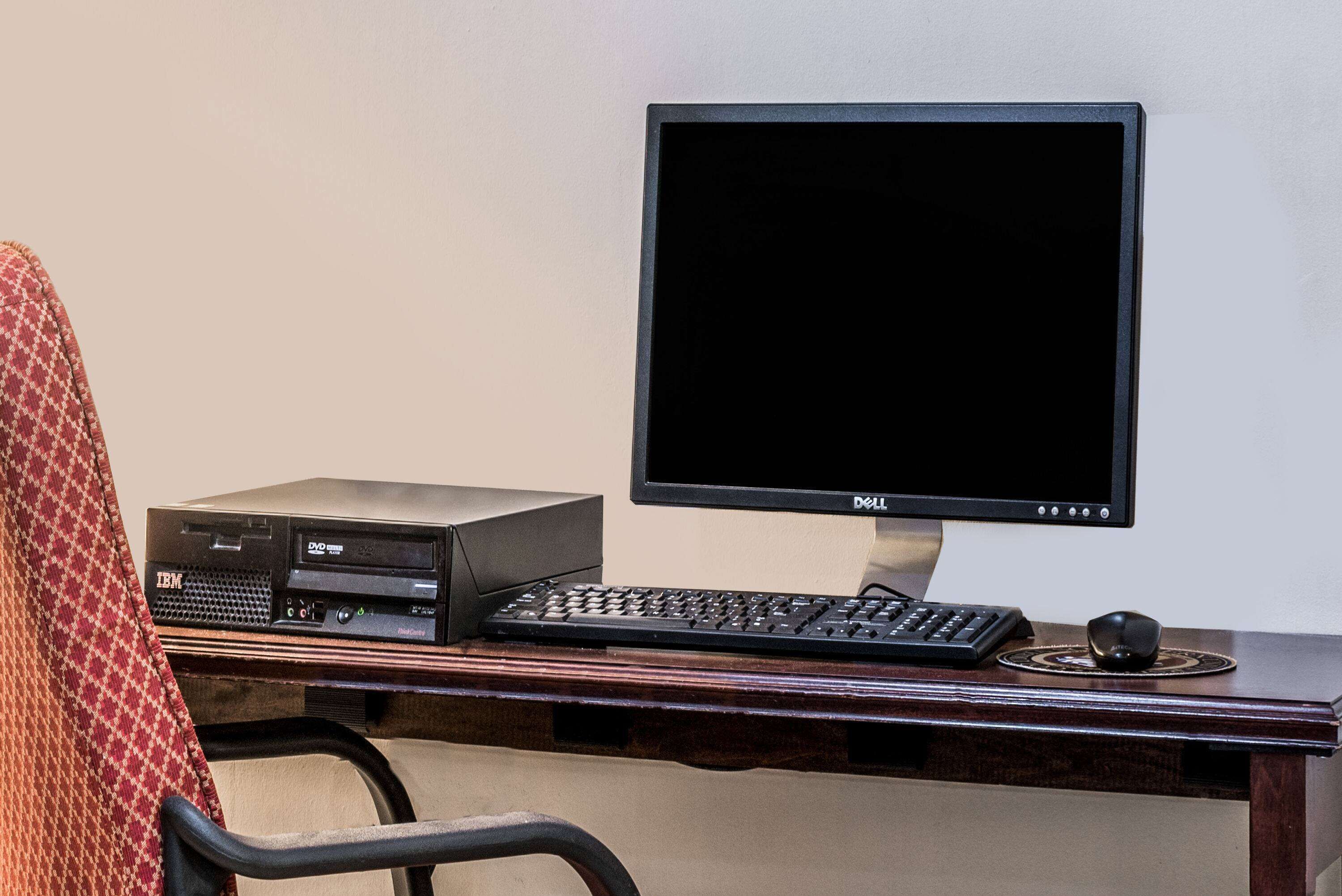 A computer desk with a monitor, keyboard, and an IBM server.