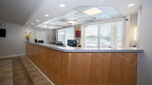 A reception area with a wooden counter, a flat-screen TV, and a fire extinguisher. - Baymont by Wyndham Lumberton NC (Lumberton)