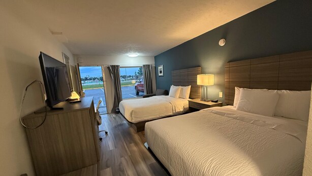 A hotel room with two beds, a desk, a television, and a window with curtains. - Baymont by Wyndham Lumberton NC (Lumberton)