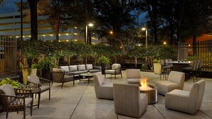 Un espacio de patio al aire libre con arreglos de asientos, una chimenea y luces ambientales.
