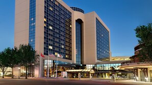 A Marriott hotel with a modern glass facade, a covered entrance, and flags. - Chattanooga Marriott Downtown (Chattanooga)