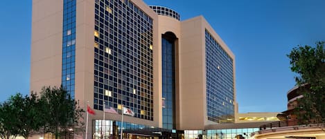 A Marriott hotel with a modern glass facade, a covered entrance, and flags.