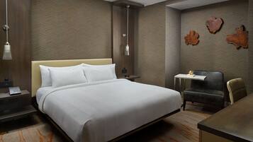 Een hotelkamer met een groot bed, een bureau, een stoel, een kleine tafel en decoratieve wandkunst.