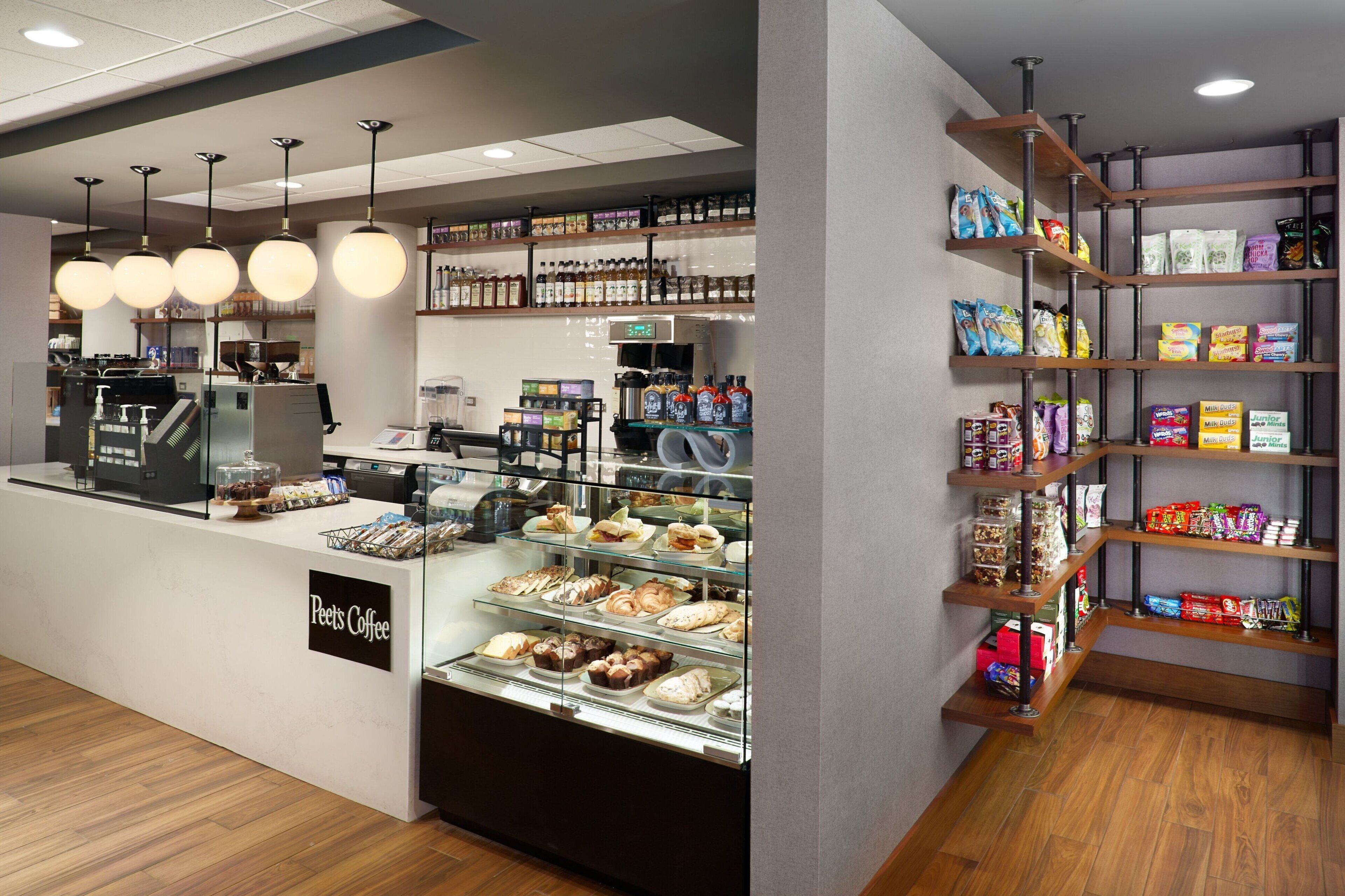 Ein Peet's Coffee Kaffeehaus-Interieur mit einer Theke, Auslagen und Regalen voller Snacks und Getränke.