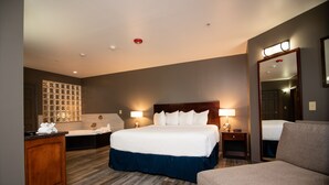 Une chambre d’hôtel dotée d’un grand lit, d’un coin salon, d’une coiffeuse avec un miroir et d’un luminaire fixé au mur.