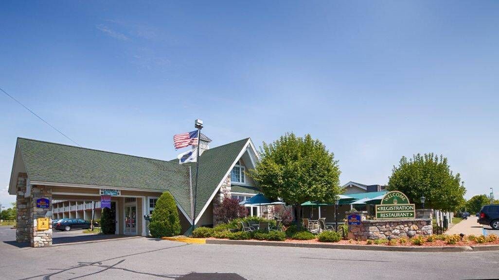 A motel with a green roof, an American flag, and a sign indicating a restaurant.