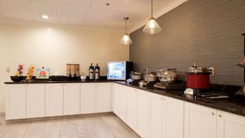 Una cocina moderna con armarios blancos, encimera negra y diversos electrodomésticos, incluyendo una cafetera, una cocedora de arroz y un tostador.