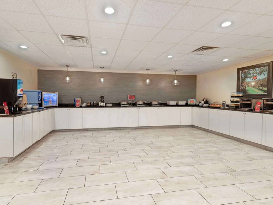 Une cuisine spacieuse avec des meubles blancs, un carrelage au sol et des luminaires suspendus.