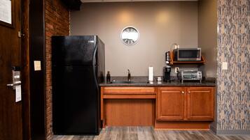 A compact kitchen with a black refrigerator, wooden cabinets, a microwave, and a sink.