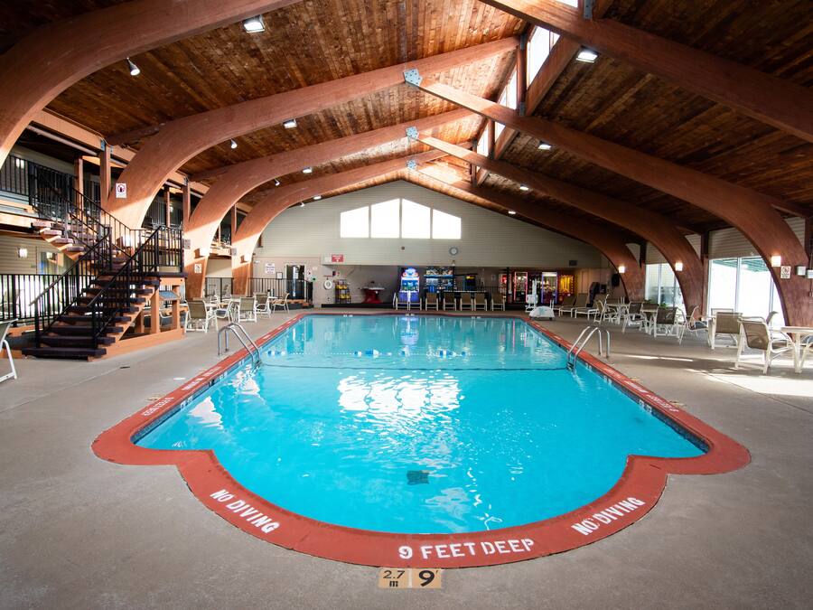 Une piscine intérieure avec un plafond en bois et un panneau indiquant une profondeur de 2,7 mètres (9 pieds) placé au bord.