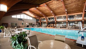 Une piscine intérieure à plusieurs niveaux, dotée de chaises longues et d’un espace repas.