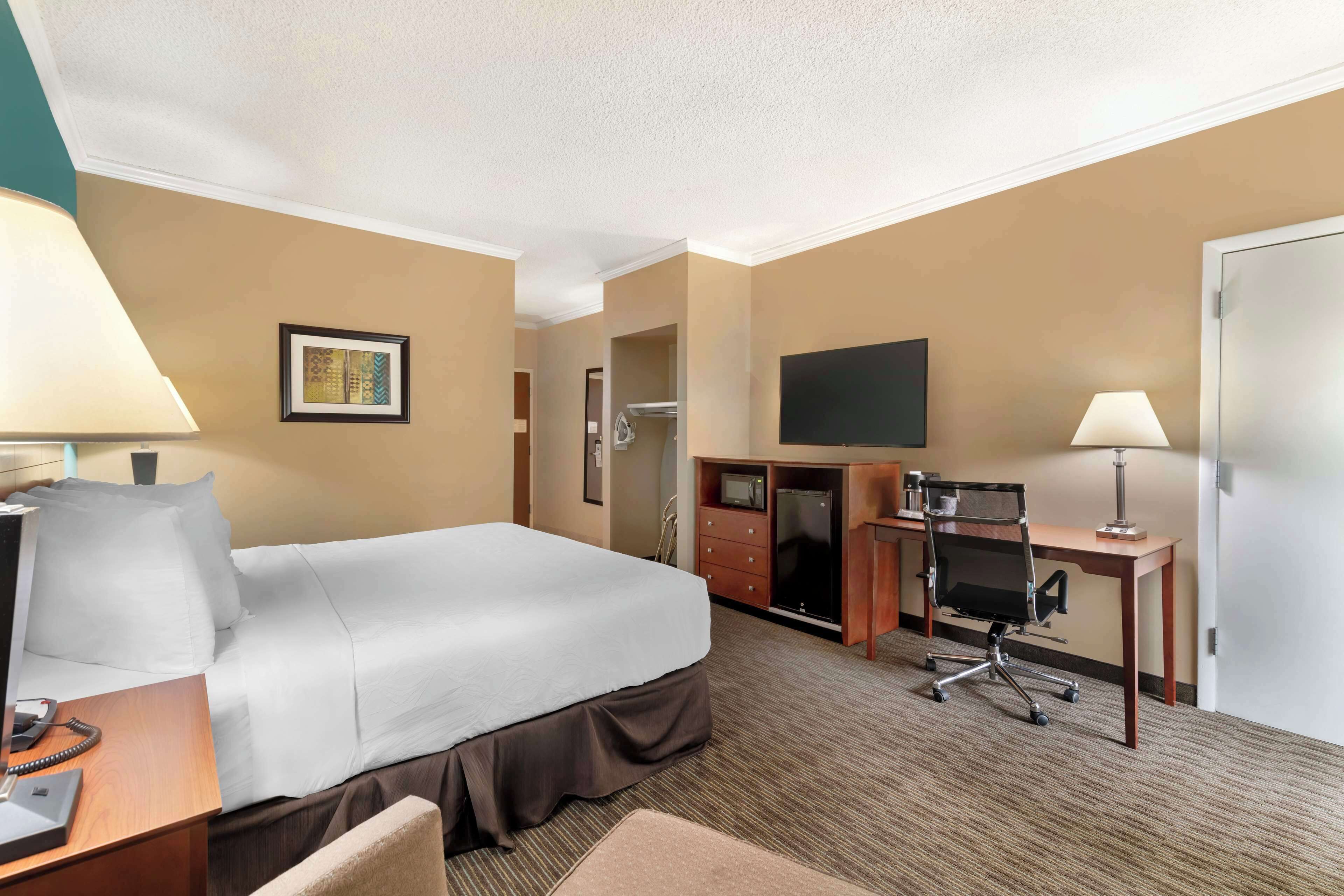 Een hotelkamer met een groot bed, een bureau met stoel, een televisie en een kledingkast.