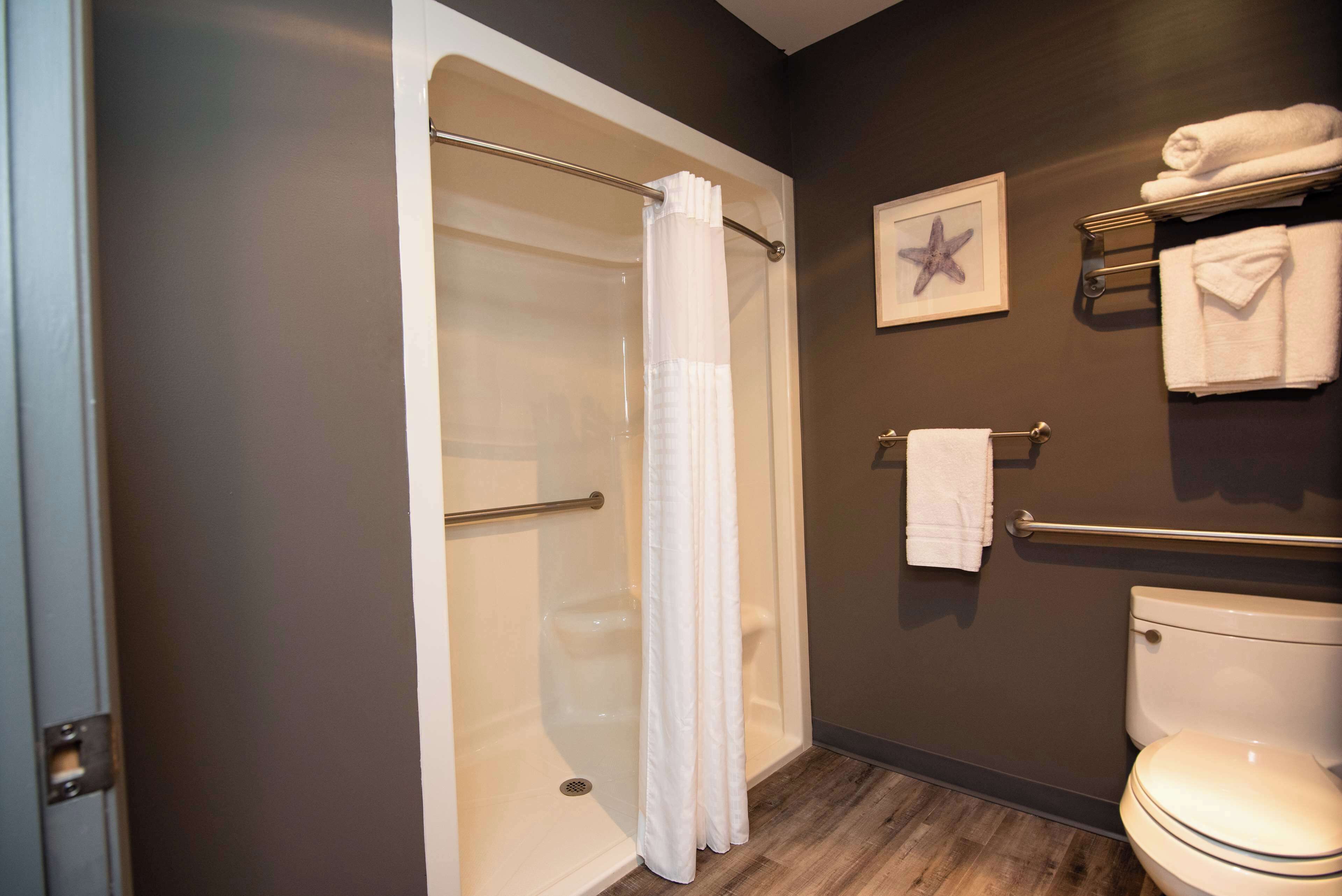 Une salle de bain équipée d’une baignoire, d’un rideau de douche, de toilettes et d’un porte-serviettes avec des serviettes.