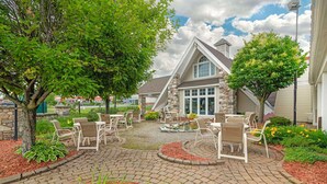 Un espace patio avec des sièges d’extérieur et un bâtiment en pierre en arrière-plan.