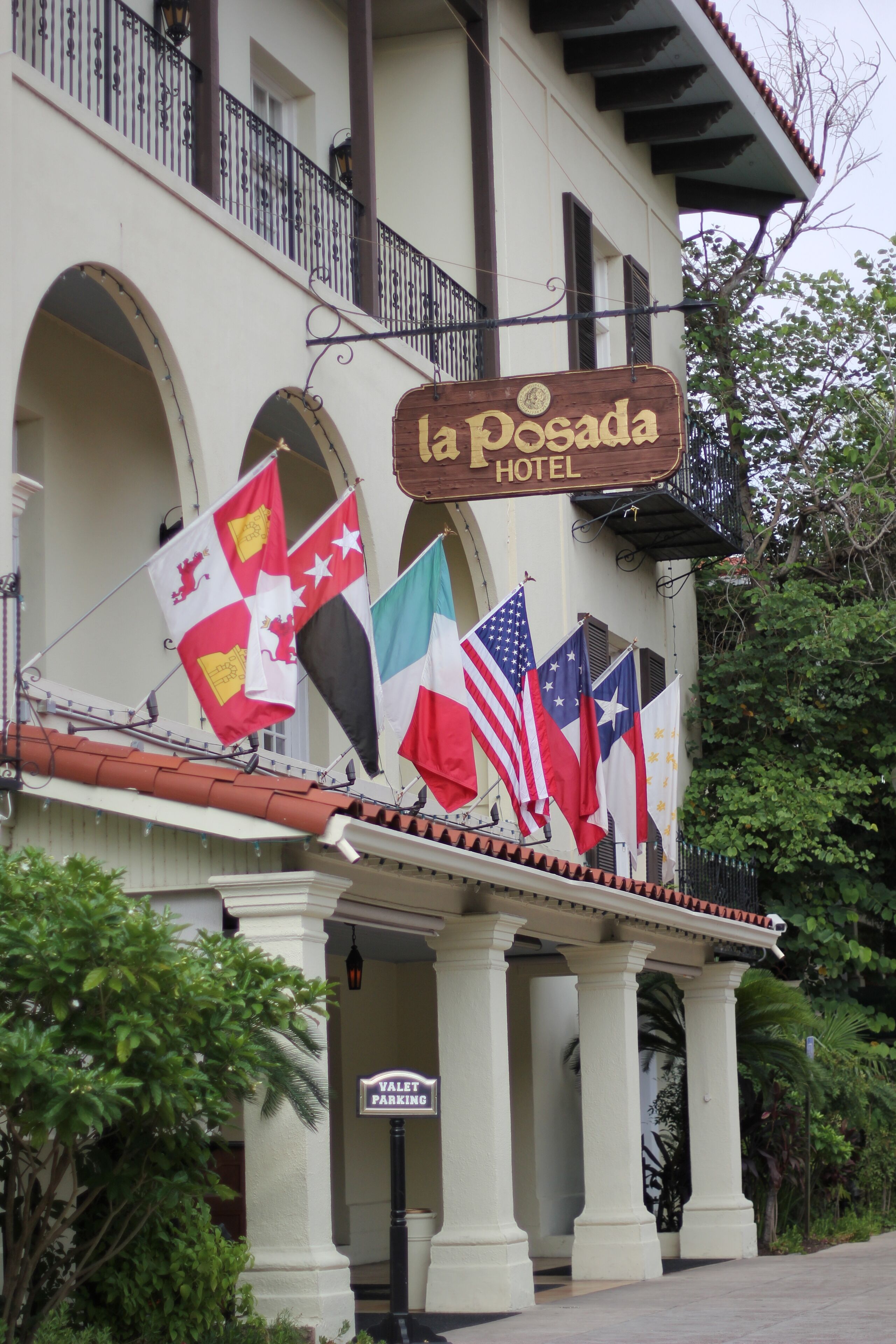 Un hotel con un letrero que dice 'la Posada Hotel' y varias banderas.