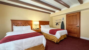 Ett hotellrum med två sängar, trägavlar, en trädörr och en väggmonterad strykbräda.
