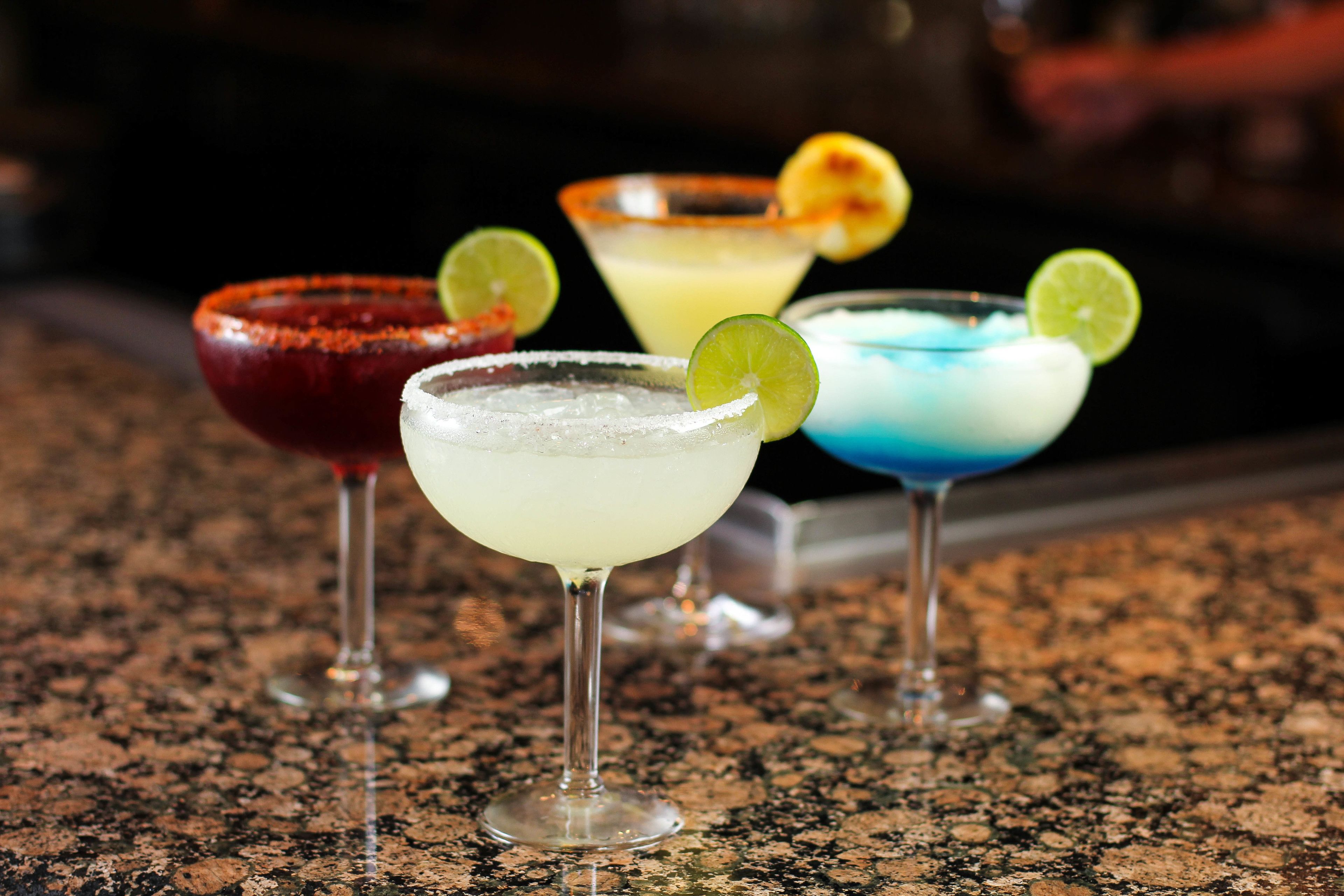 Four cocktails on a granite countertop.