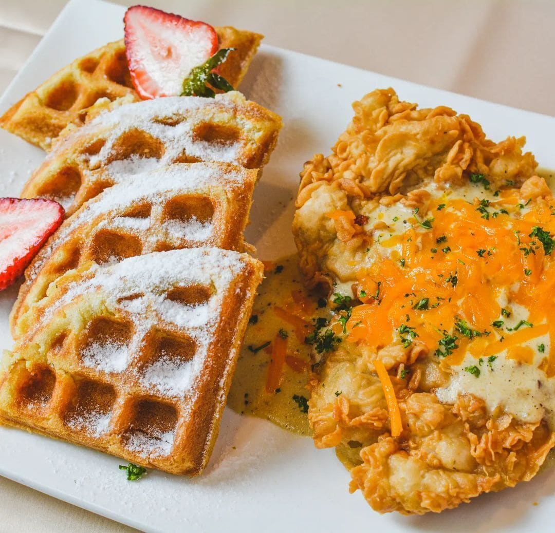Een bord met wafels, roerei en aardbeien.