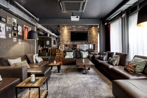 Un salon moderne avec des canapés en cuir, une cheminée, un téléviseur à écran plat et un projecteur.