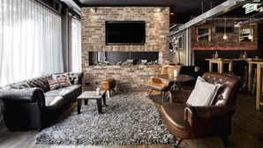 Een moderne woonkamer met een open haard van baksteen, leren banken en een flatscreen-televisie.