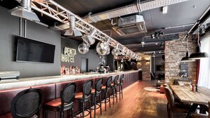 Een bar met een lange toonbank, meerdere barkrukken, een televisie en een bakstenen muur.