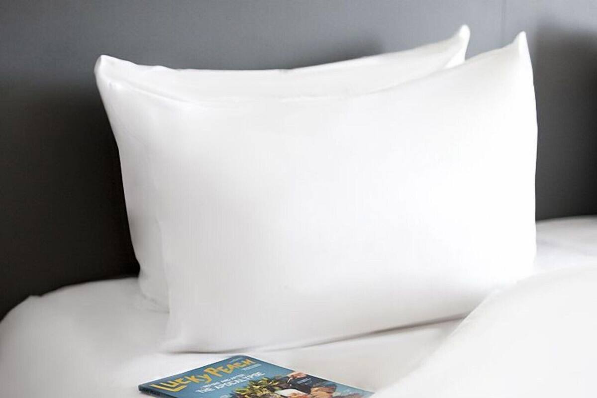 Un oreiller blanc sur un lit, avec un magazine posé dessus.