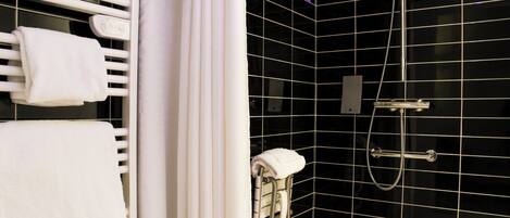 Une salle de bain moderne avec un mur recouvert de carreaux noirs, un porte-serviettes blanc, une douche équipée d’un pommeau de douche à main et des toilettes dotées d’un support pour le papier essuie-tout.