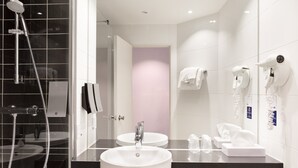 A modern bathroom with two sinks, a shower, and a hairdryer.
