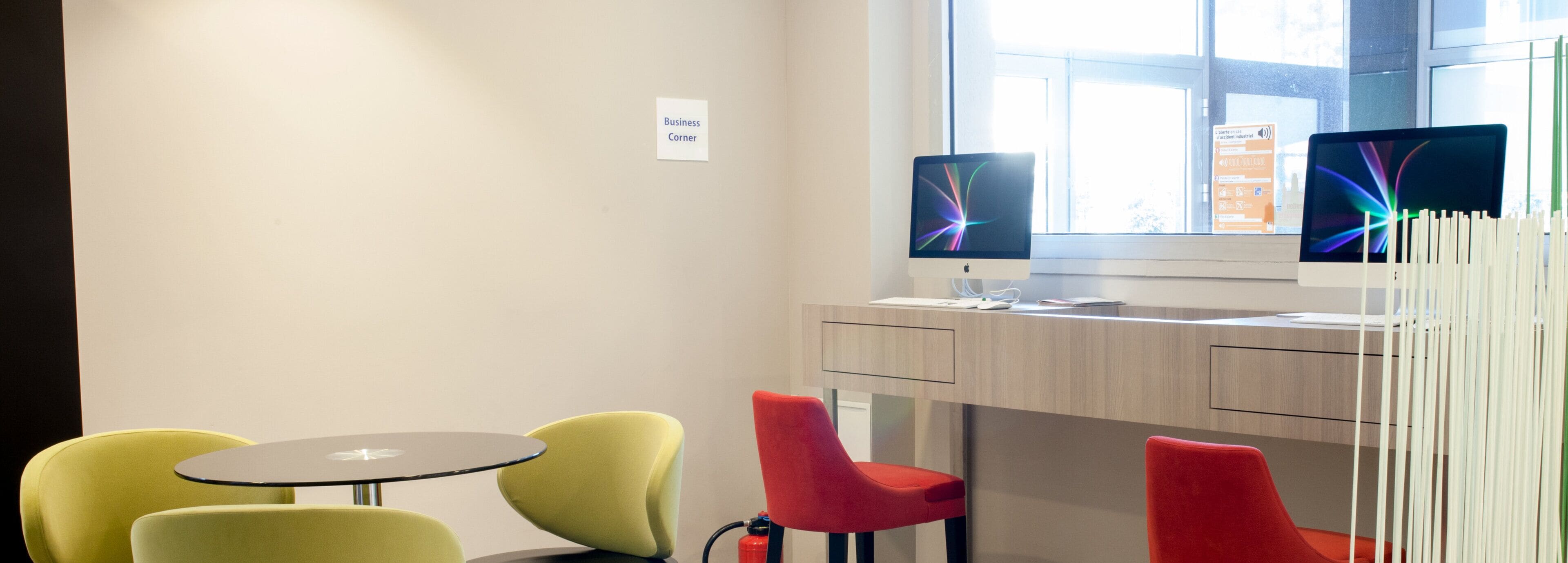 A modern workspace with two monitors, a table, and four chairs.