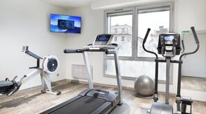 A fitness room with a treadmill, elliptical, stationary bike, and exercise ball.