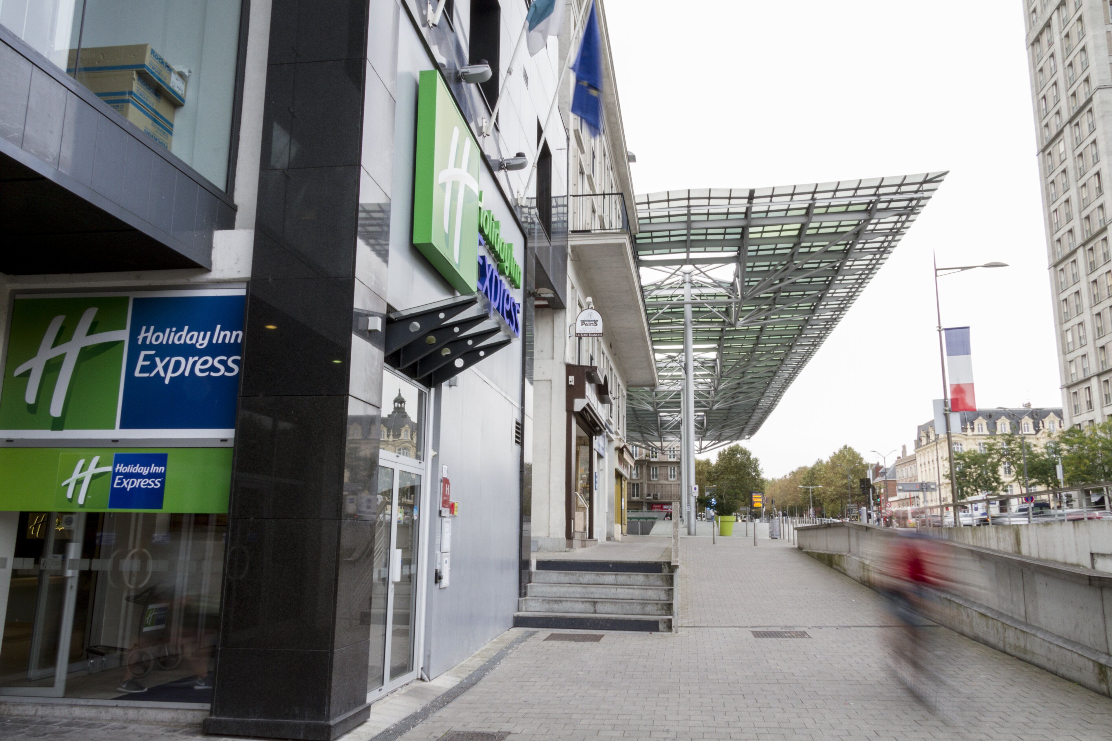 A building with a Holiday Inn Express sign, a covered walkway, and a view of the street.