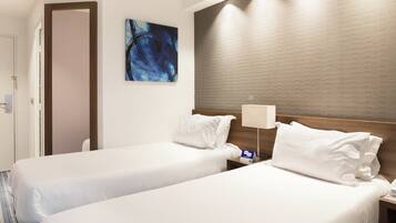 A hotel room with two beds, a painting on the wall, and a textured wall panel.