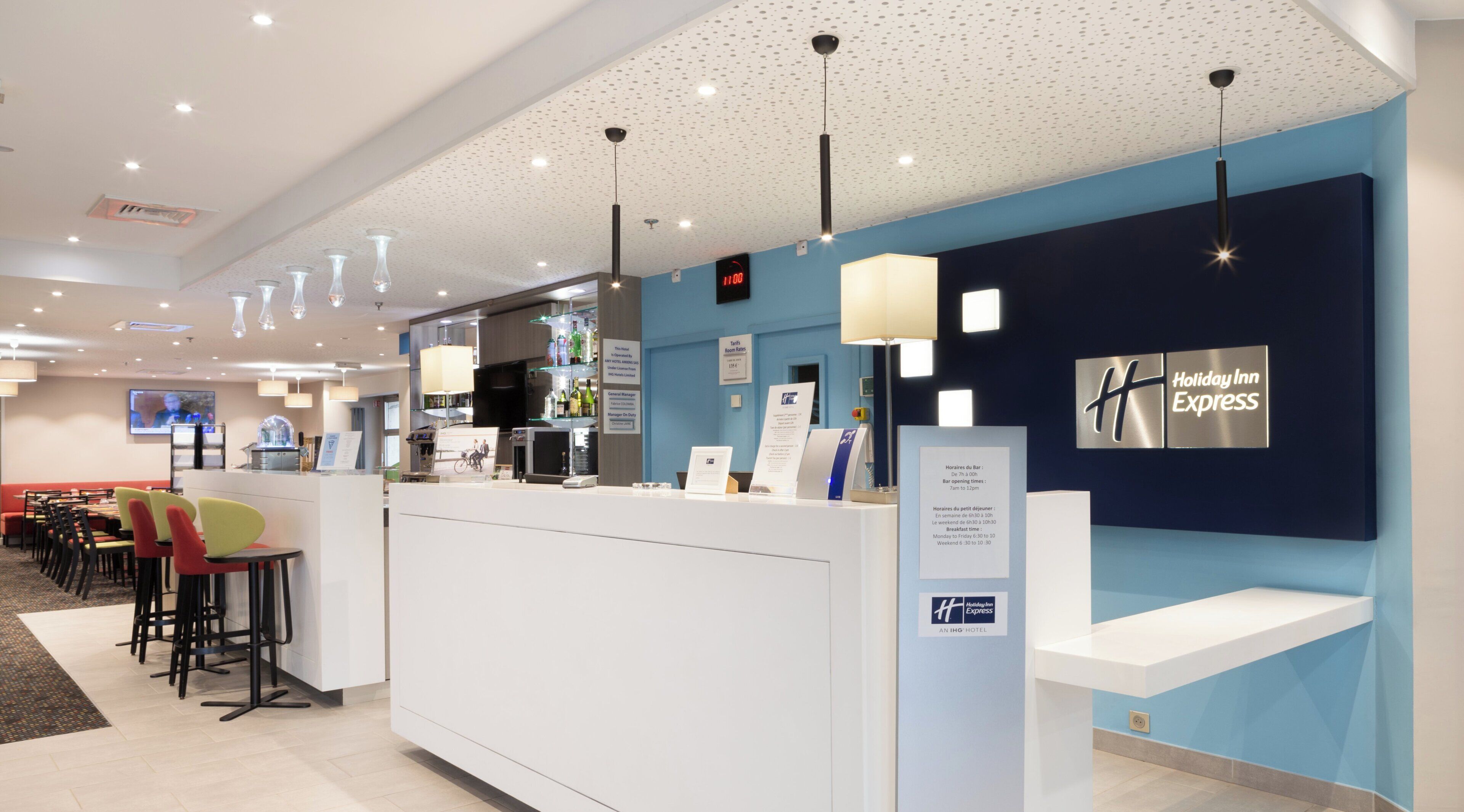 A hotel reception area with a counter, seating, and a wall displaying the hotel name.