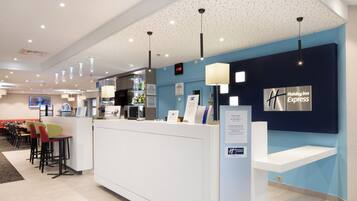 A hotel reception area with a counter, seating, and a wall displaying the hotel name.