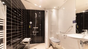 A modern bathroom with a black-tiled shower area, a white toilet, and a sink with a mirror.