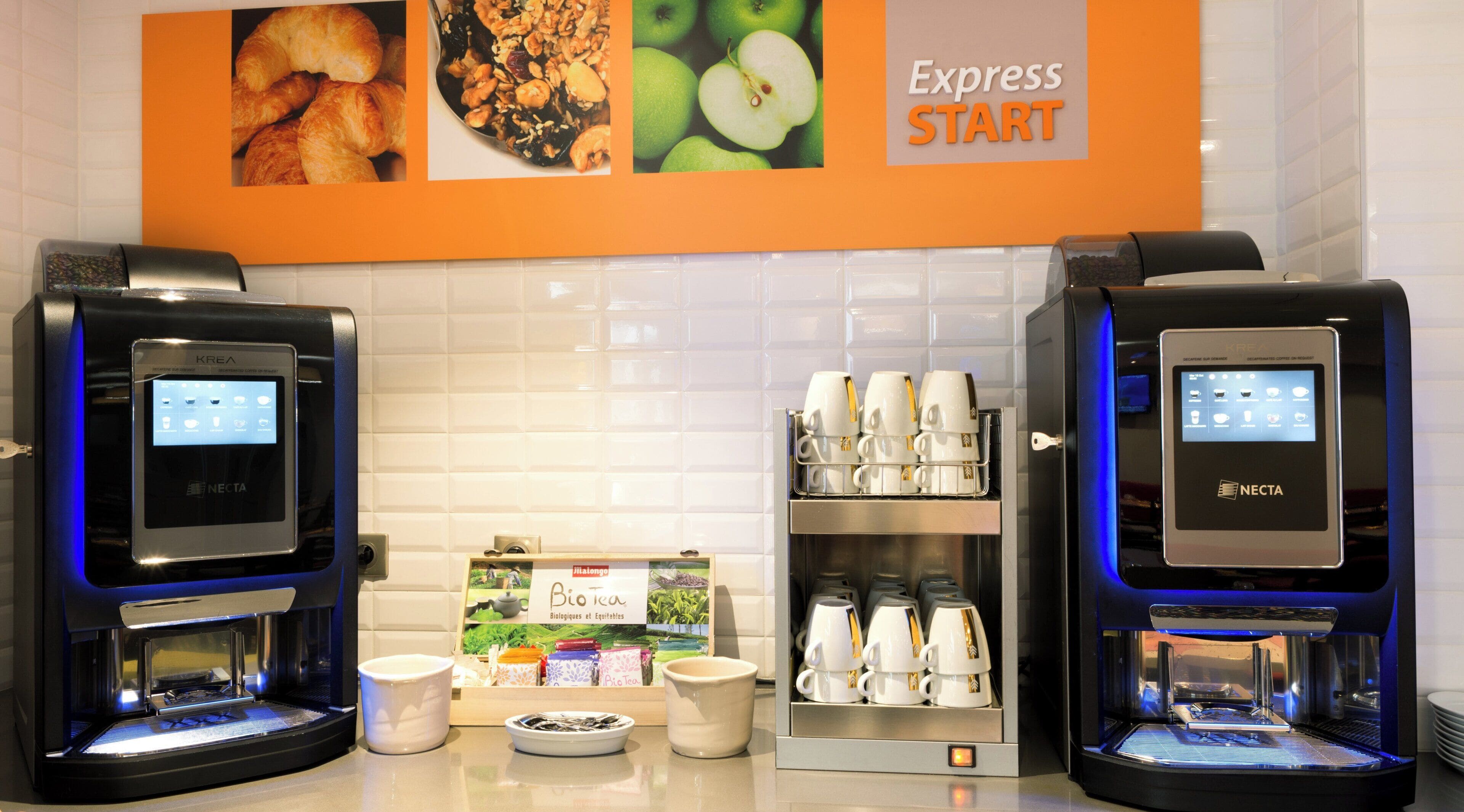 Two KREA coffee machines with digital interfaces, a display of coffee cups, and a 'Bio Tea' sign.