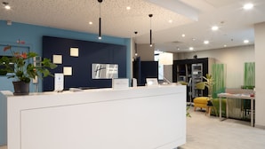 A modern reception desk with a blue accent wall, a potted plant, and a sign for Holiday Inn Express.