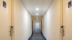 A hotel hallway with doors numbered 508 and 505, a blue carpet, and a ceiling with recessed lighting.