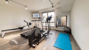 A gym with cardio machines, a blue mat, and a TV displaying 'Holiday Inn Express'.